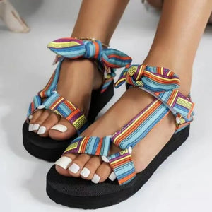 Bow-tie platform sandals with colorful stripe pattern and ankle ties.