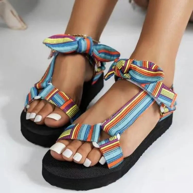 Bow-tie platform sandals with colorful stripe pattern and ankle ties.