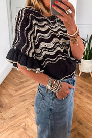 Black openwork knit sweater with white wavy pattern and ruffled sleeves.
