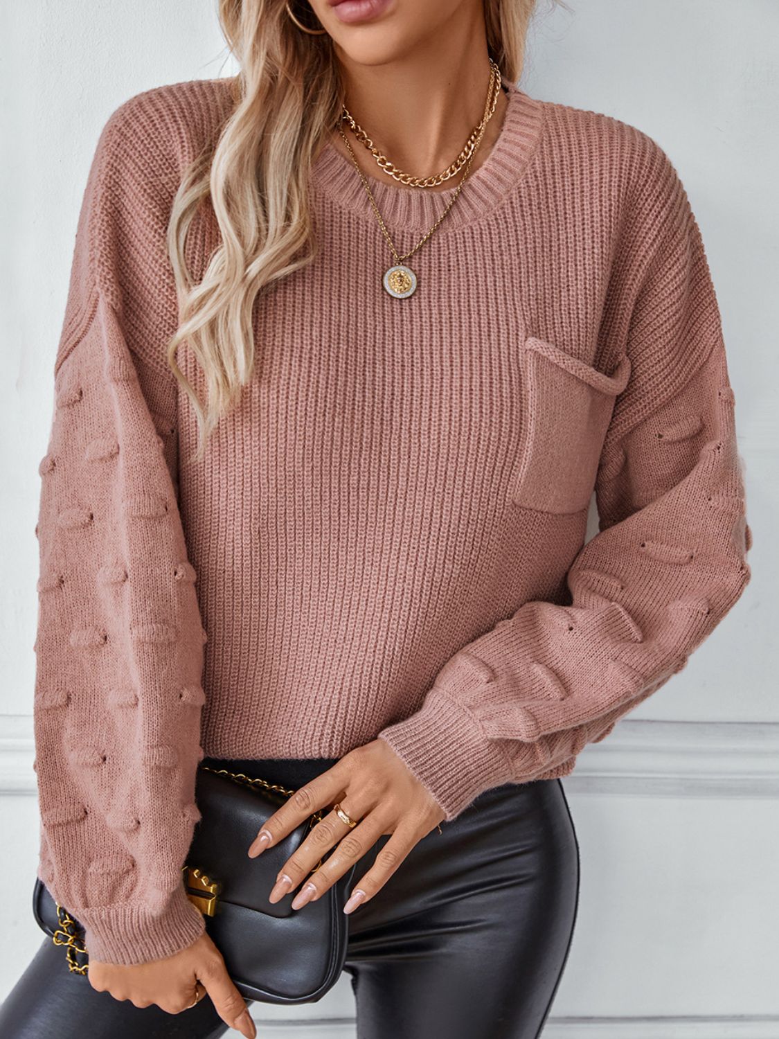 Dusty pink knit sweater with textured sleeve details and a chest pocket.