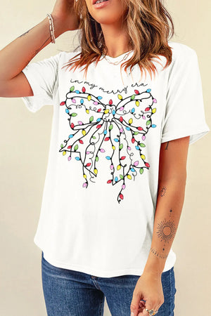 White graphic tee with holiday lights bow and "in my merry era" text