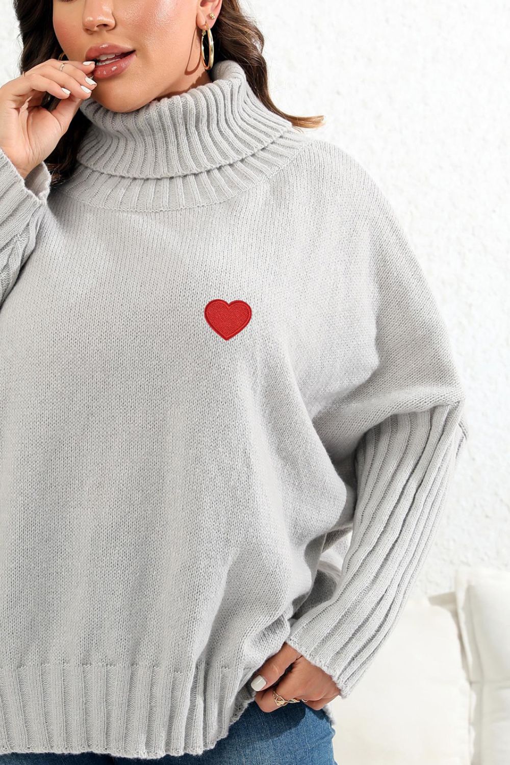 Light gray knit turtleneck sweater with red heart appliqué and ribbed sleeves.