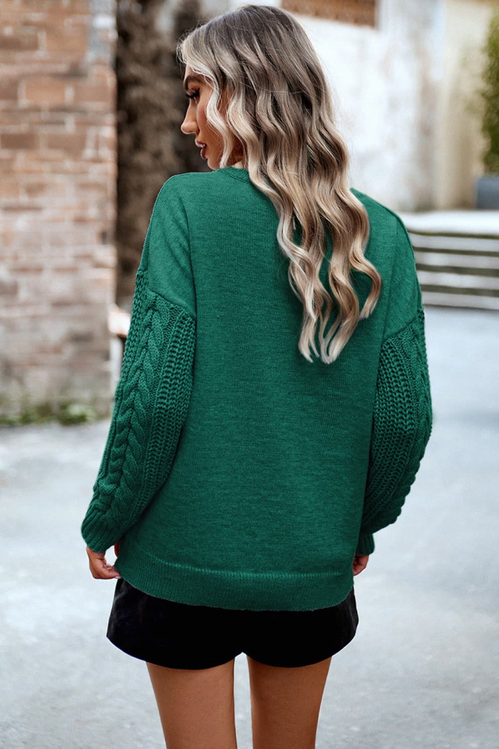 Dark green acrylic sweater with cable-knit sleeves and relaxed fit.