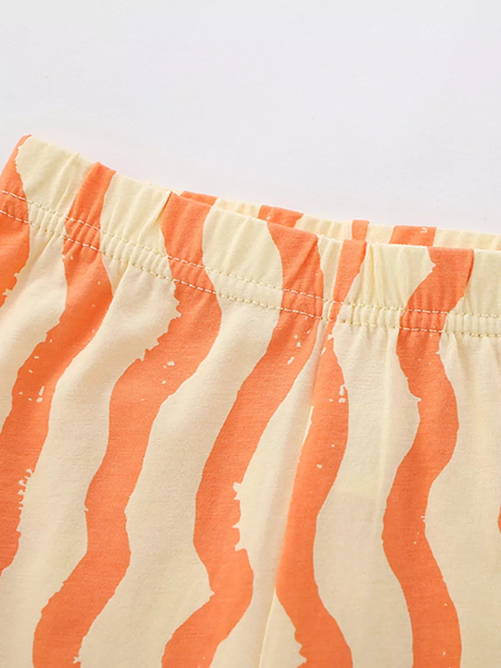 Toddler cotton shorts with orange wavy stripes and elastic waistband.