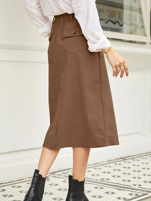 Brown midi skirt with elastic waist, buttoned pocket detail, and subtle vertical ribbing.