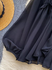 Black chiffon blouse with ruffled tie-front detail and gathered cuffs.