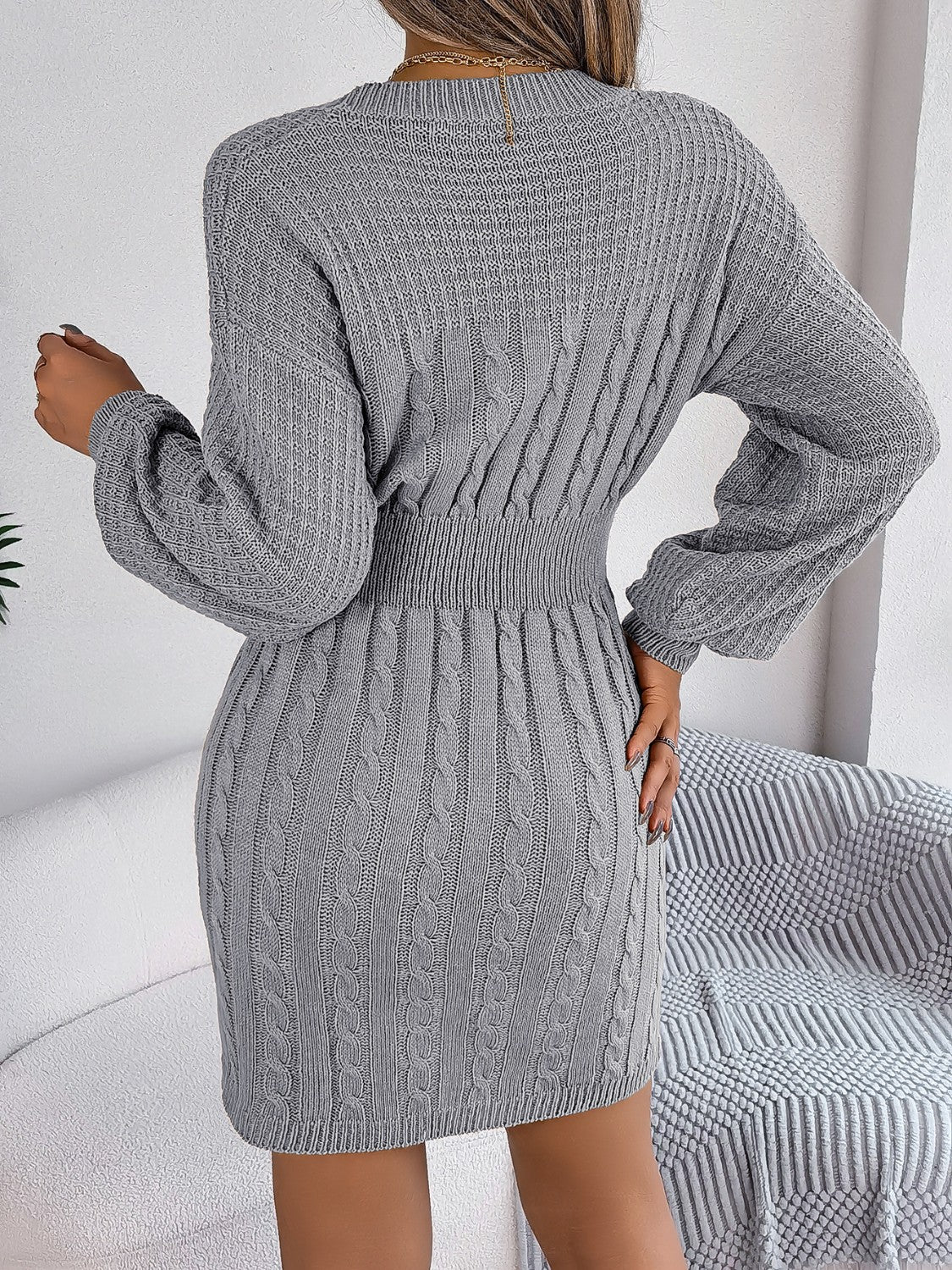 Cable knit mini dress in charcoal with a cinched waist and long sleeves.