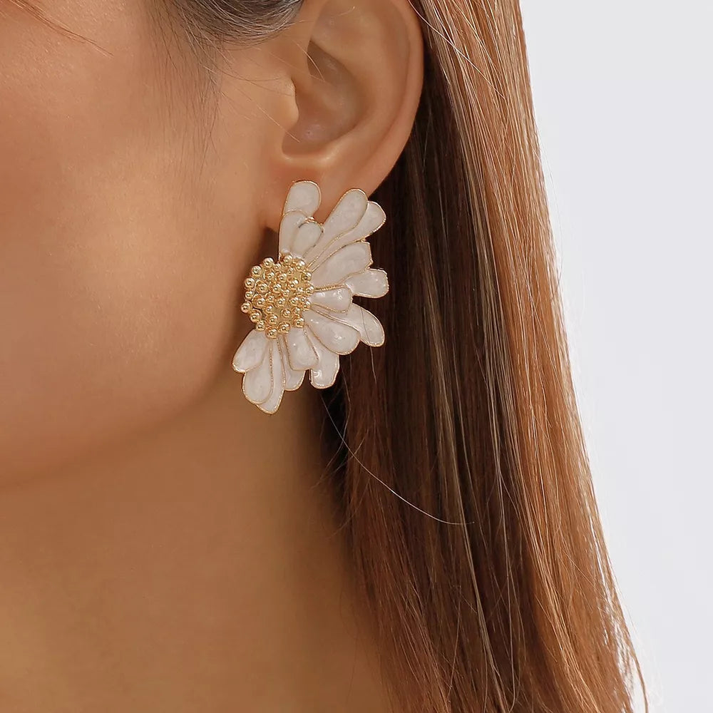 White flower stud earrings with textured gold center detail.