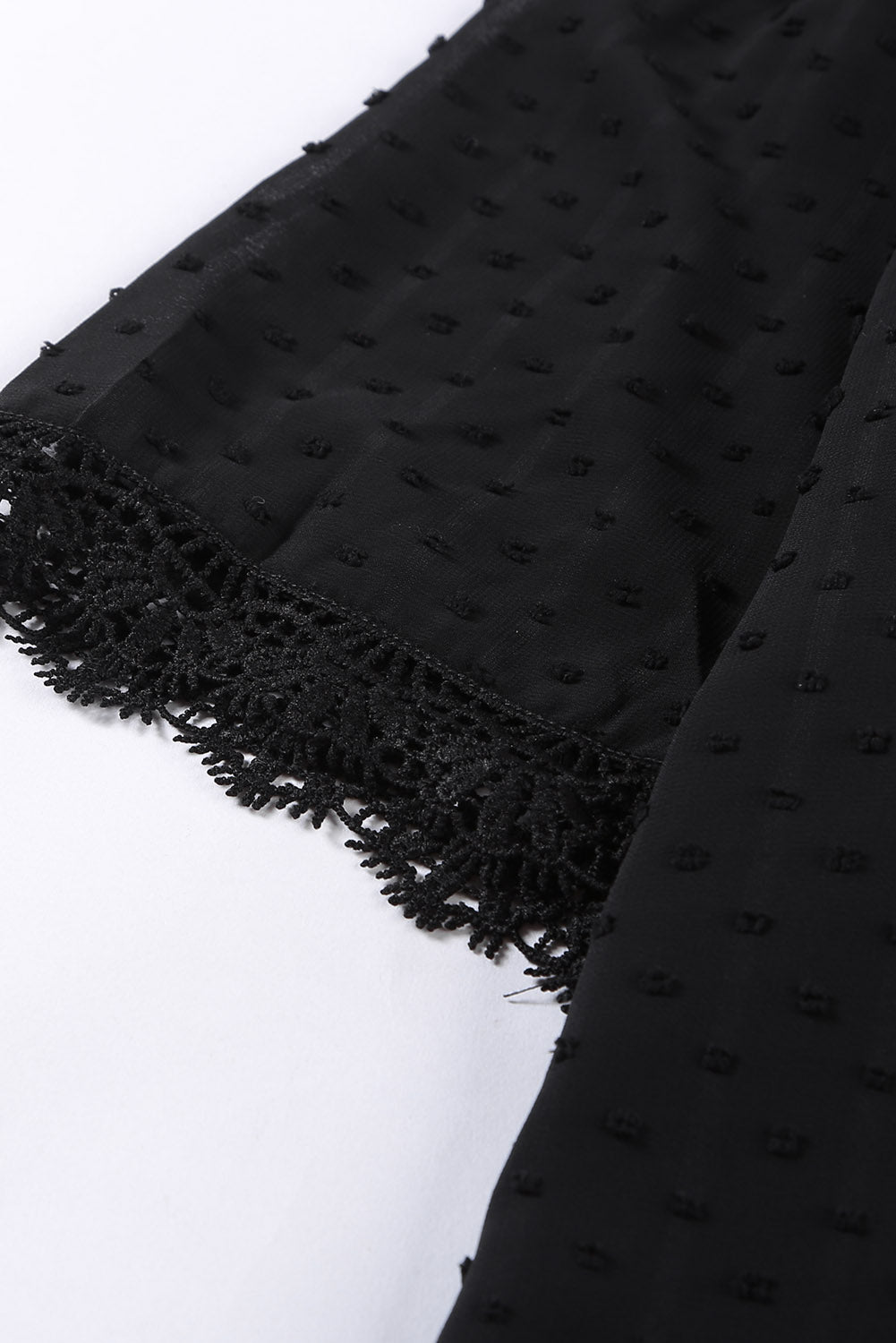Black textured dot blouse with lace trim detail on sleeve cuff.