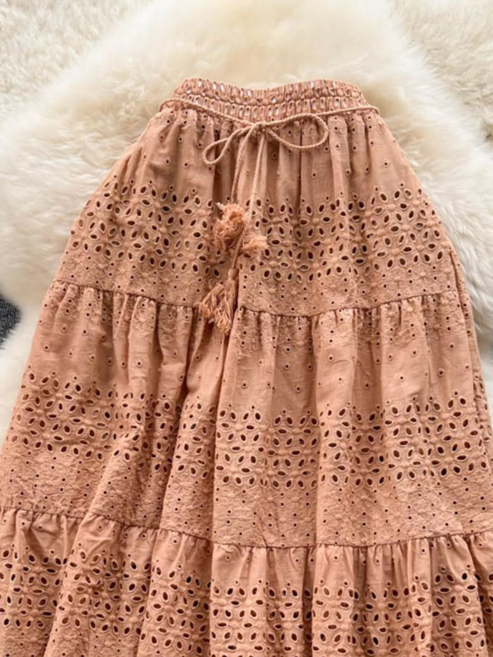 Light brown eyelet tiered maxi skirt with drawstring waist and tassel detail.