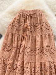 Light brown eyelet tiered maxi skirt with drawstring waist and tassel detail.