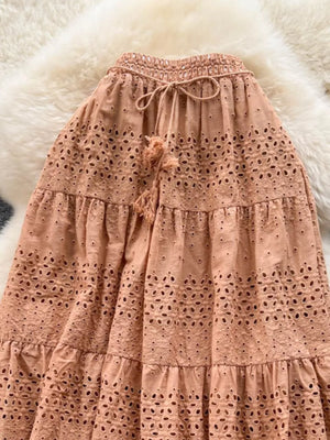 Light brown eyelet tiered maxi skirt with drawstring waist and tassel detail.