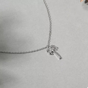 Silver palm tree pendant necklace with clear stones on a delicate chain.