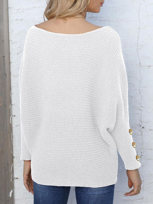 White batwing knit sweater with boat neck and pearl button cuff detail.