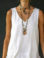 White tiered ruffled hem V-neck sleeveless dress with layered necklaces.