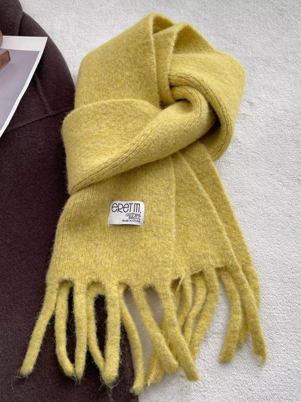 Plush yellow scarf with fringe detail and a cozy knit texture.