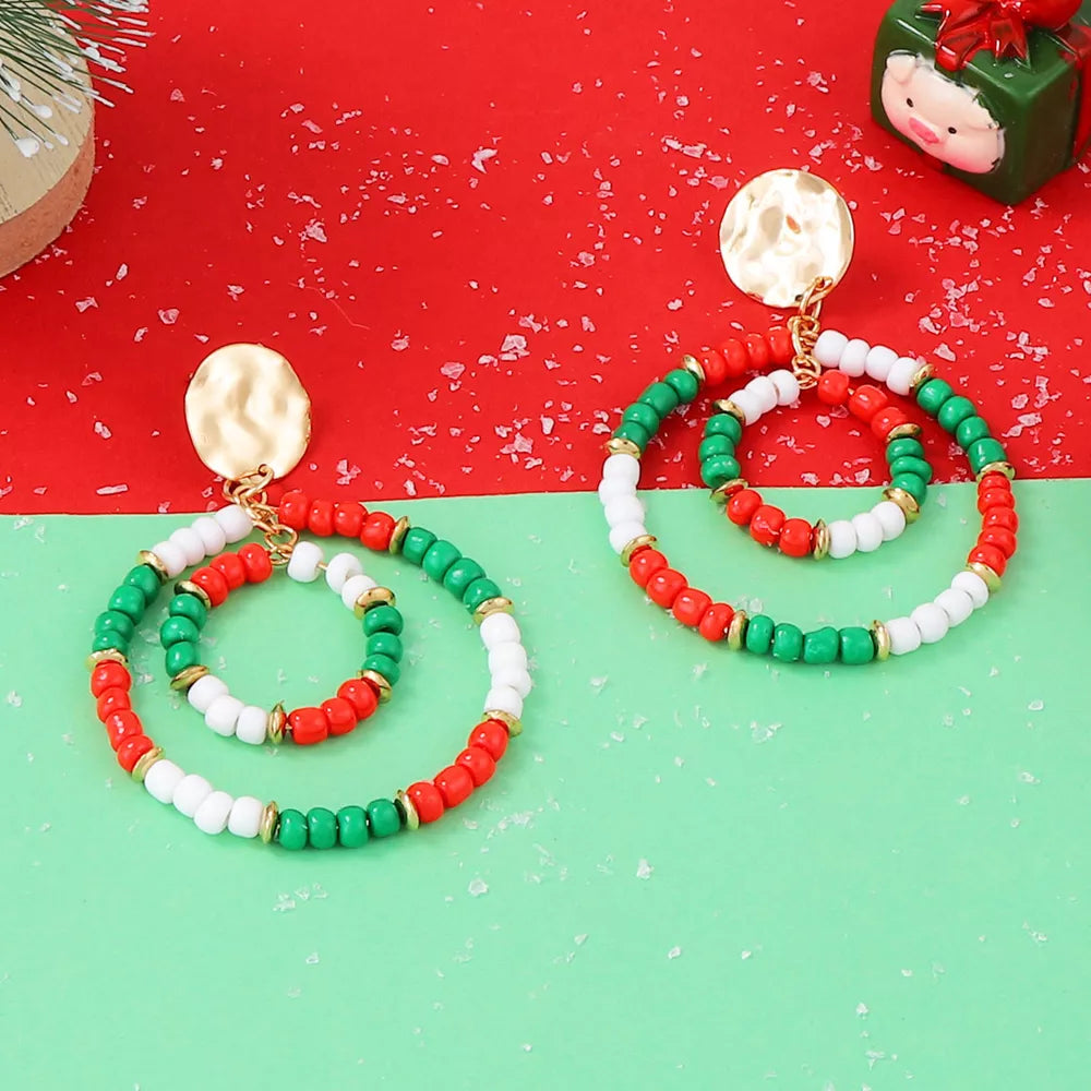 Festive beaded hoop earrings in red, white, and green with gold accents and hammered gold tops.
