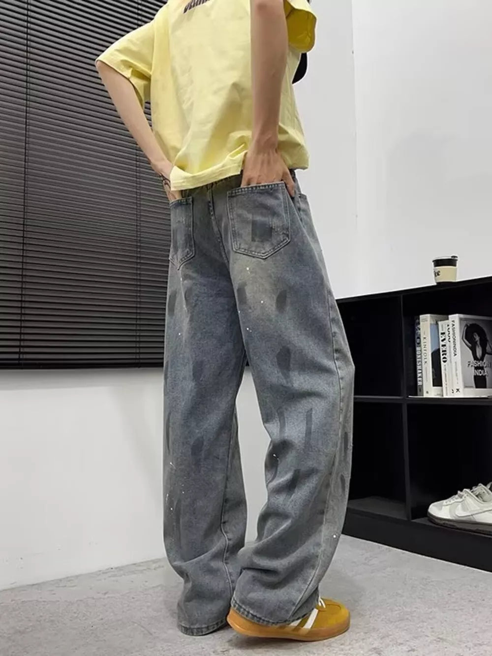 Men's wide-leg denim jeans in blue with paint splatters and graphic details.