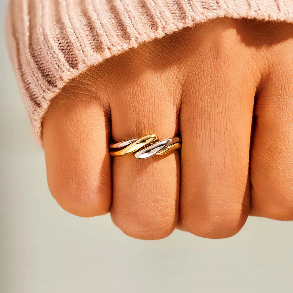 Two-tone gold intertwined open ring with twisted detail on a finger.