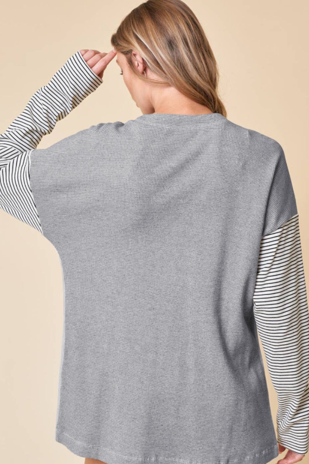 Light gray waffle knit cardigan with contrast black and white striped sleeves.