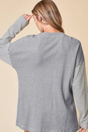 Light gray waffle knit cardigan with contrast black and white striped sleeves.