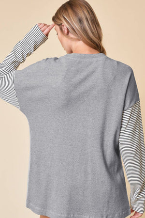 Light gray waffle knit cardigan with contrast black and white striped sleeves.