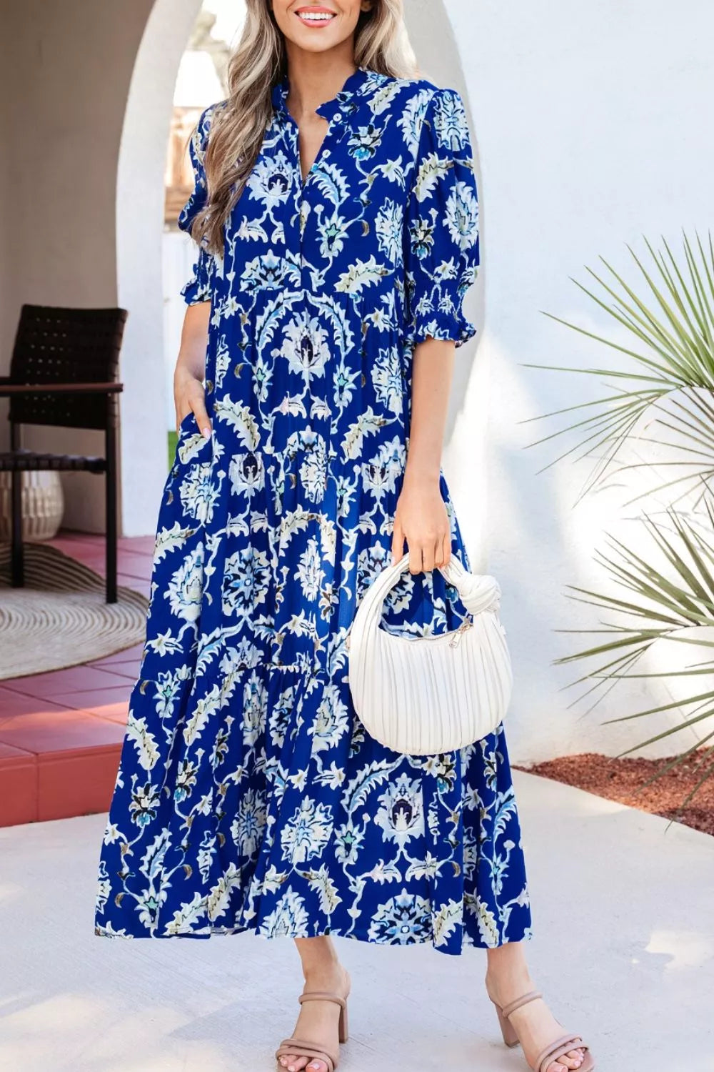 Vibrant floral maxi dress with frilled collar, buttoned front, and tiered skirt.
