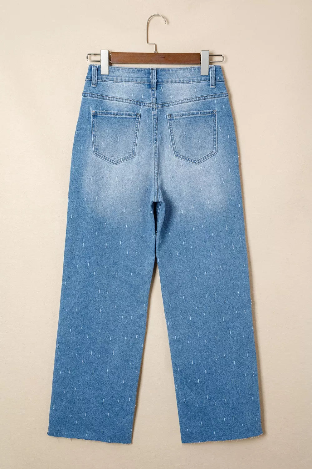 High-rise light wash denim jeans with subtle all-over pattern and raw hem.