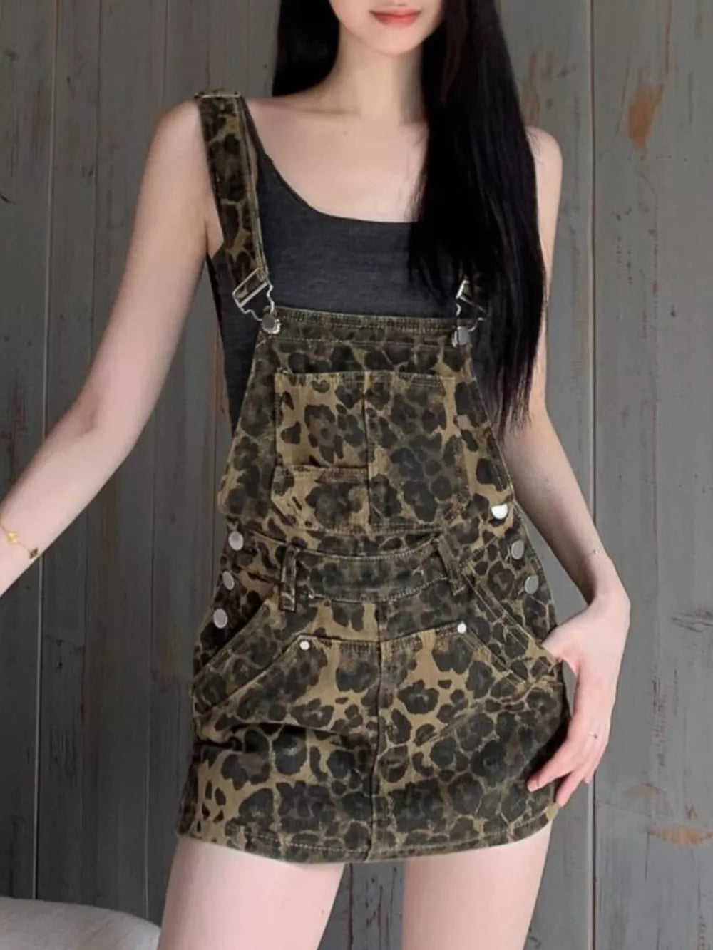 Denim overall dress with leopard print in army green, adjustable straps, and buckle detail.