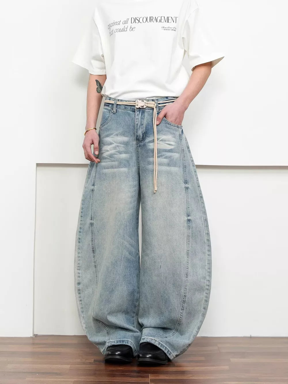Belted wide leg jeans in light blue denim with balloon silhouette and distressed details.