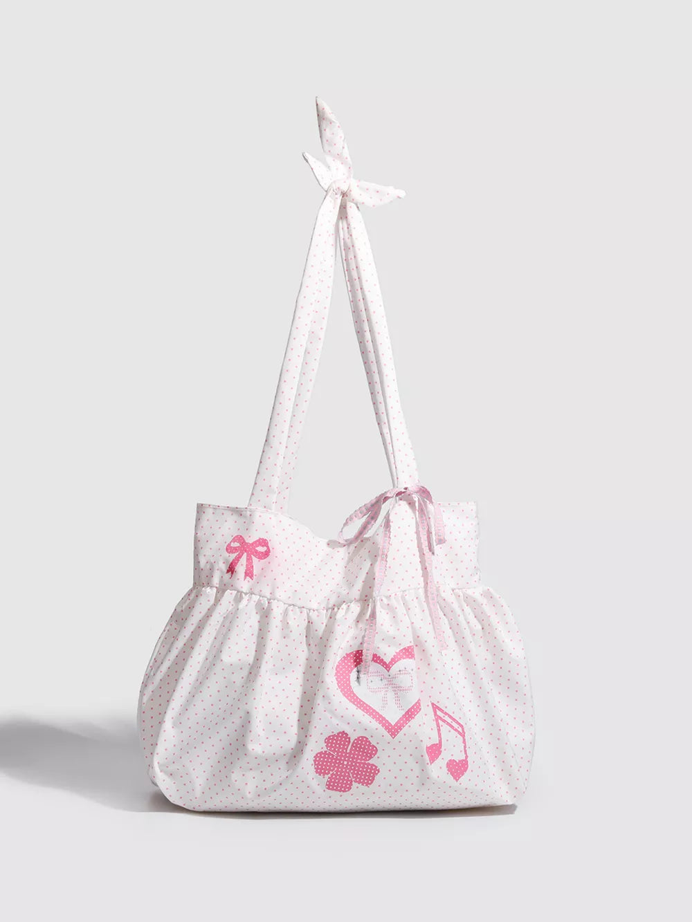 Blush pink polka dot canvas shoulder bag with heart, bow, flower, and music note appliqués.