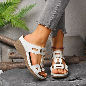 Chic white open-toe wedge sandals with gold buckle details and a textured sole.
