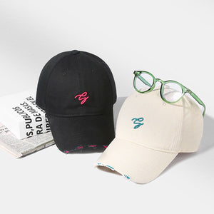 Distressed cotton baseball caps in off-white and black with embroidered logos and frayed details.