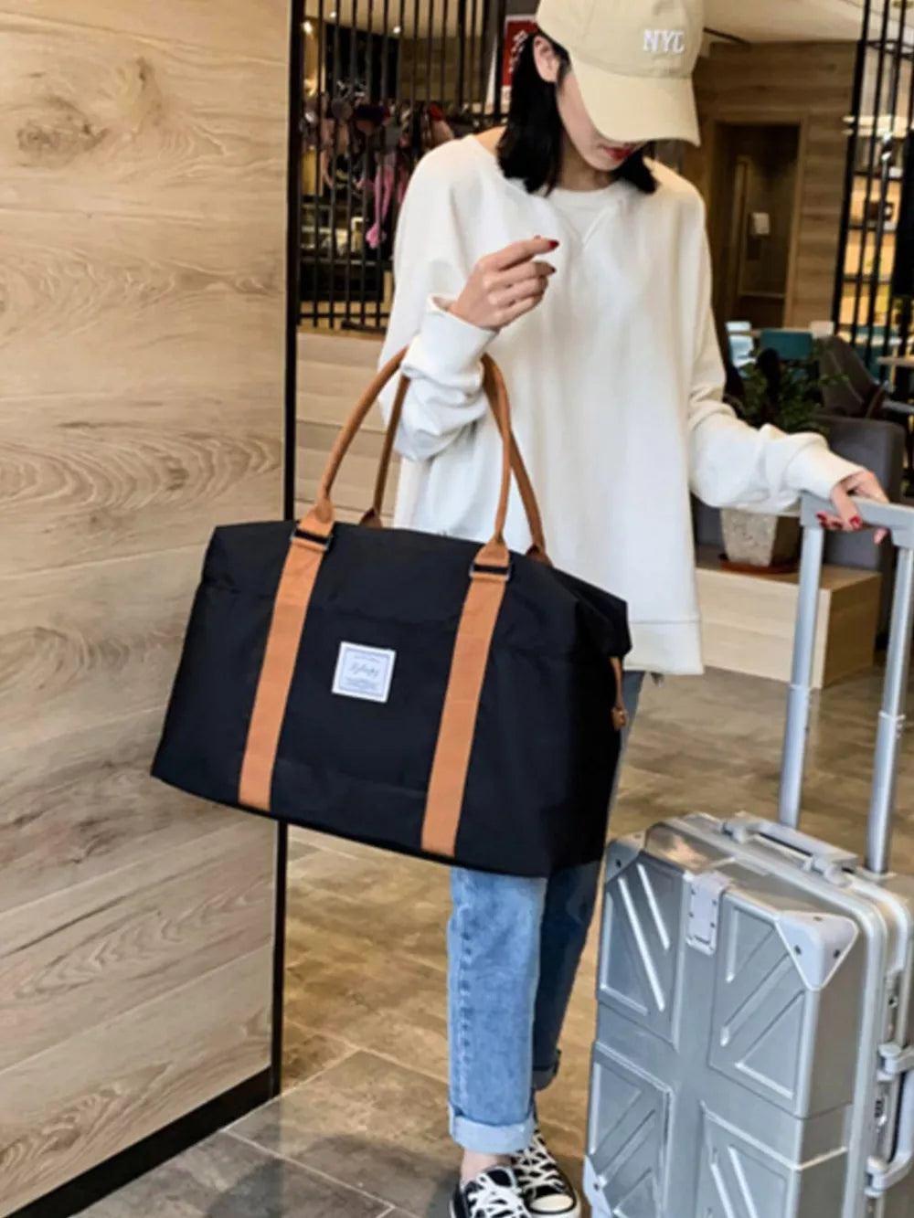 Large black Oxford cloth travel bag with contrast tan straps and handles.