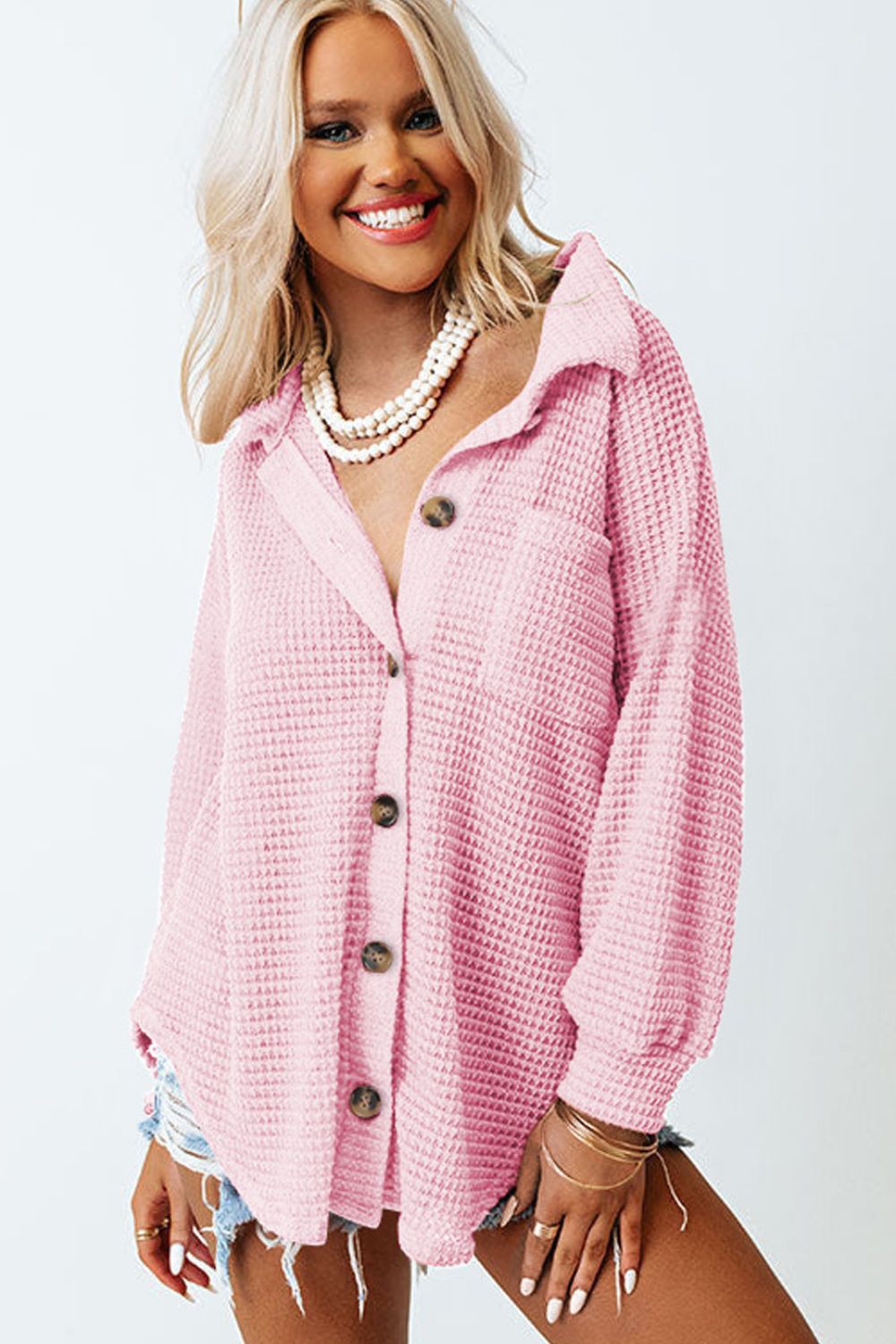 Blush pink waffle knit button-down shirt jacket with a pocket and button closure.