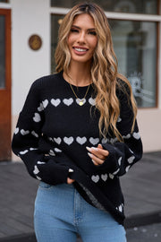 Black knit pullover sweater with white heart stripes, crewneck, long sleeves.