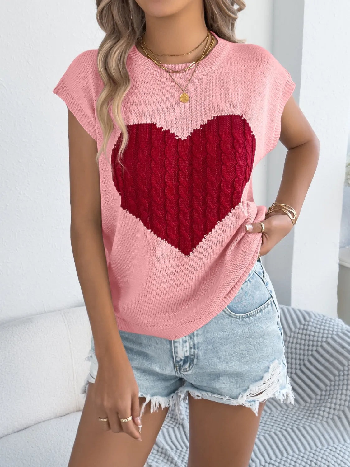 Blush pink cable knit sweater vest with a large red cable knit heart graphic.