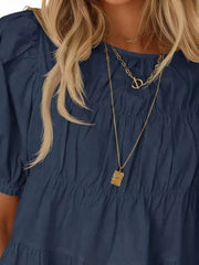 Dark blue maternity blouse with puff sleeves and tiered, ruffled smocking detail.
