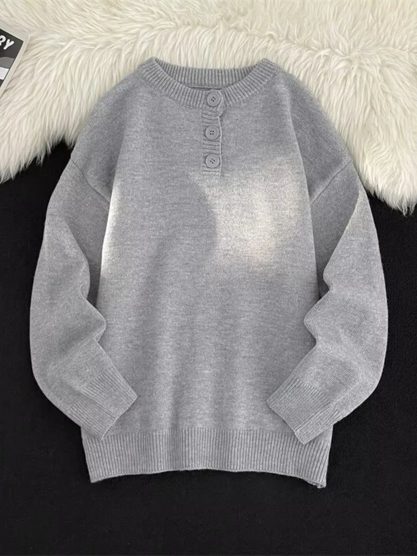 Light gray ribbed knit sweater with button detail at the neckline.