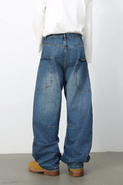 Medium wash denim balloon trousers with large front pockets and a relaxed fit.