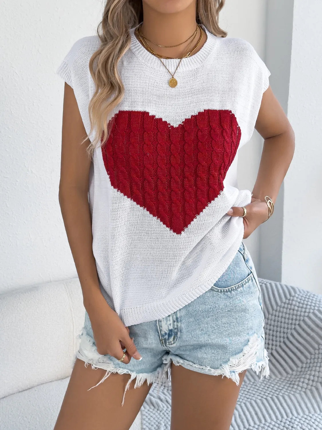 White cable knit sweater vest with red cable knit heart graphic.