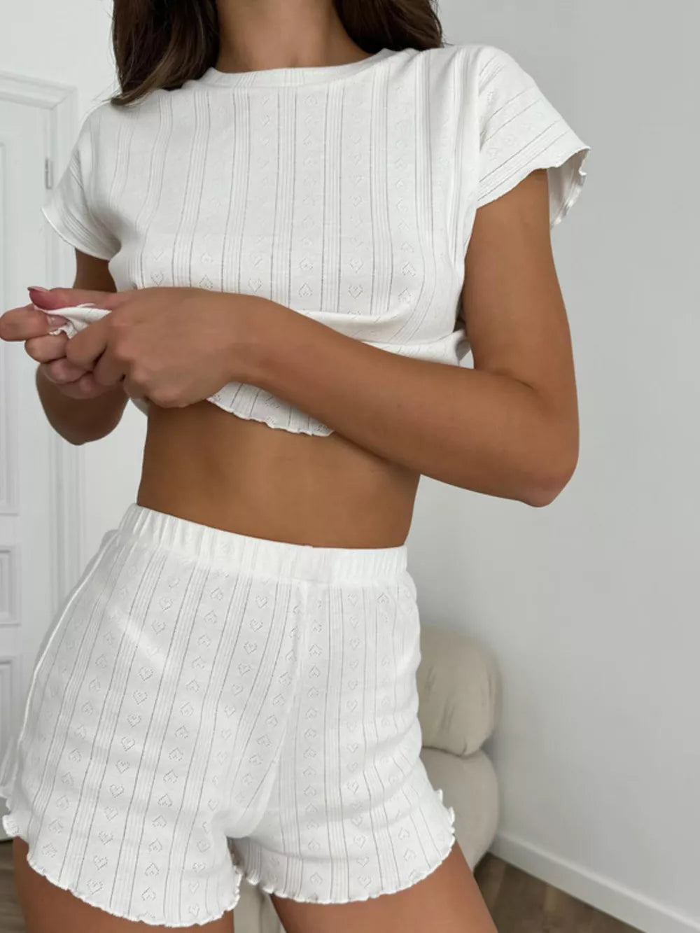White ribbed pajama set with heart pattern and ruffled hem shorts and crop top.