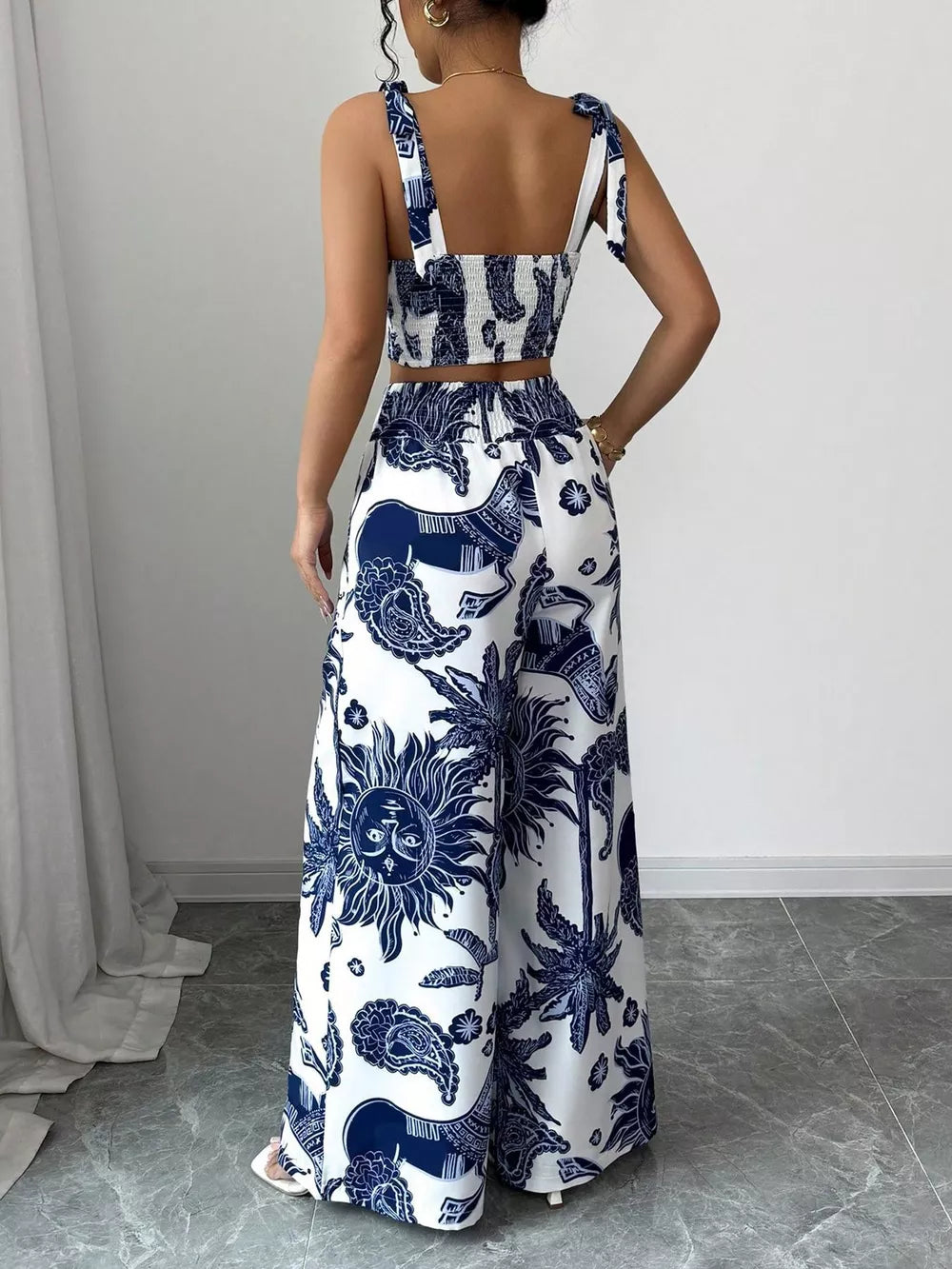 Blue and white tropical print crop top with tie straps and wide leg pants.
