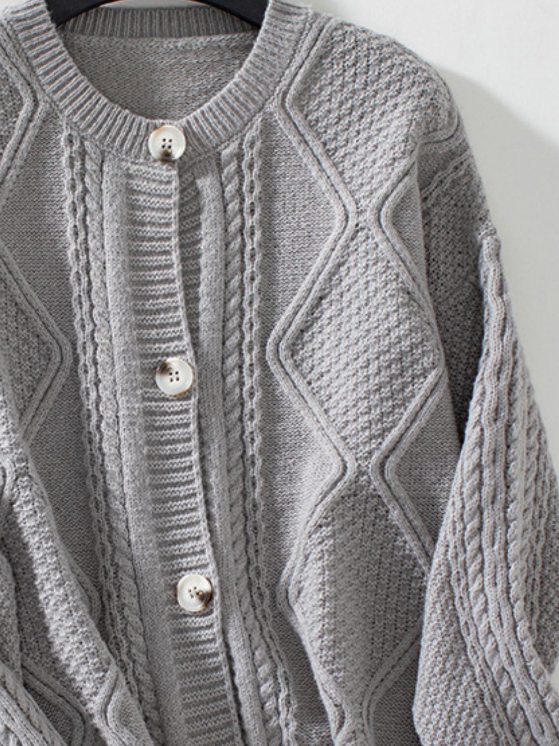 Gray cable-knit button-down cardigan with diamond and cable textures.