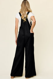 Black pleated bib wide leg jumpsuit with pockets and adjustable straps.