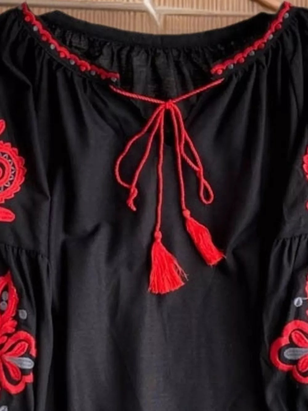Black peasant blouse with red embroidery, tie neck, and tassel details.