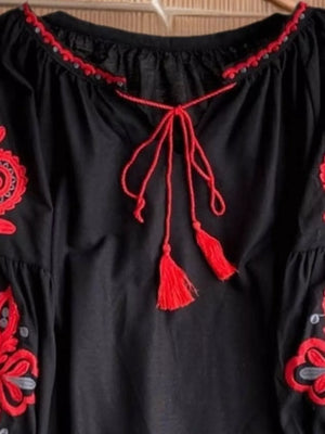 Black peasant blouse with red embroidery, tie neck, and tassel details.