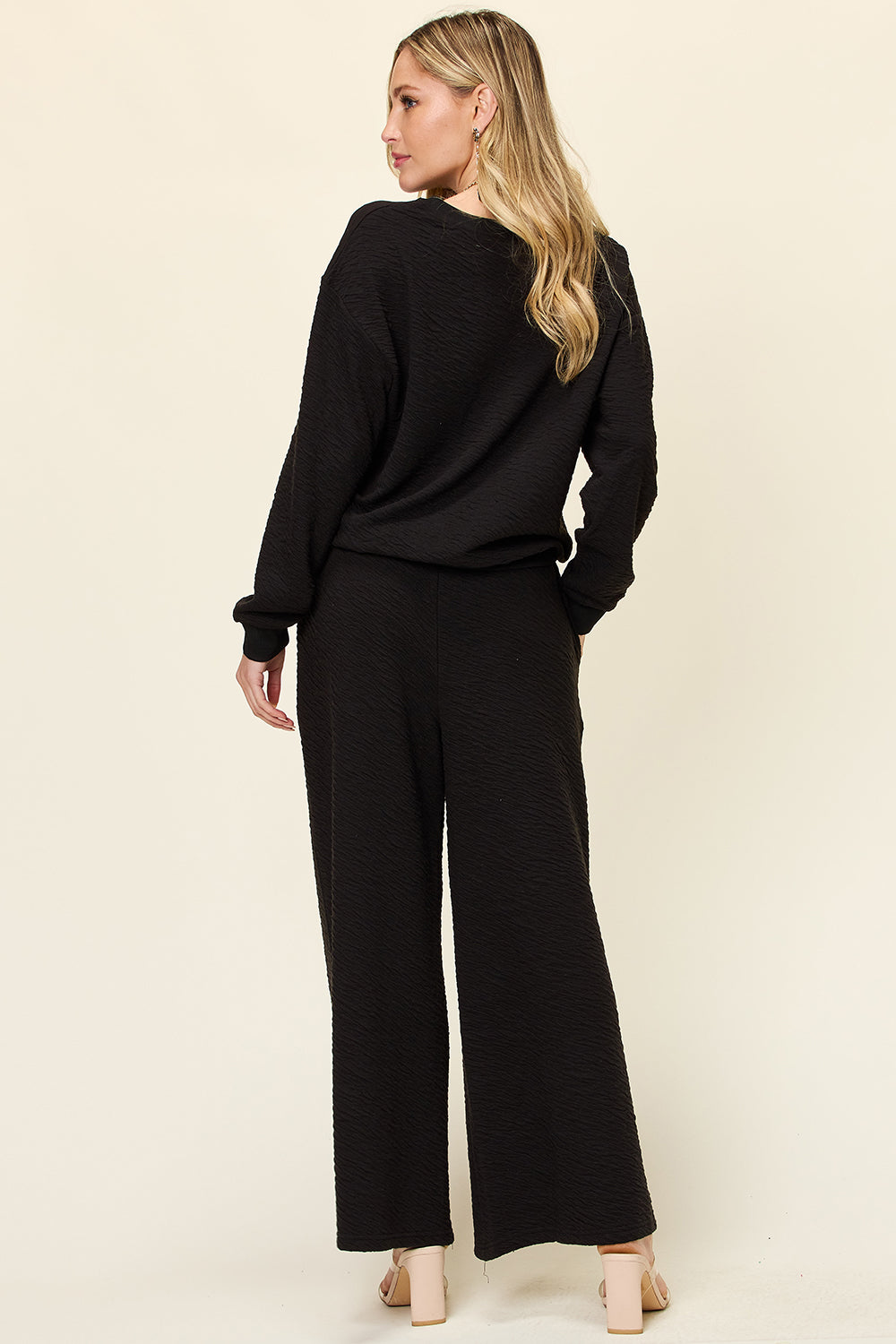 Black textured loungewear set with wide leg pants and crewneck top.