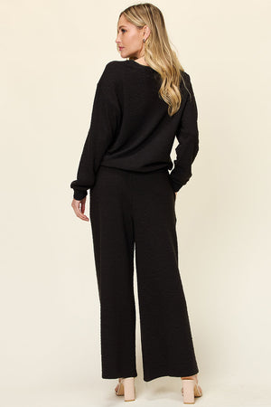 Black textured loungewear set with wide leg pants and crewneck top.