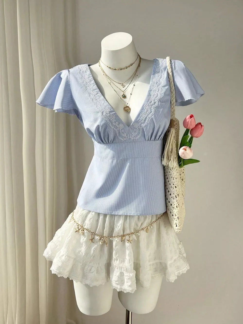 Blue striped polyester blouse with lace V-neck and flutter sleeves.